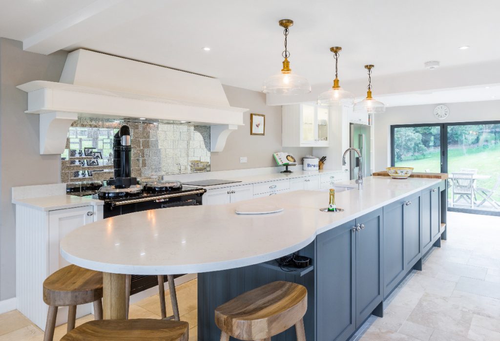 a blue shaker-style kitchen with a large island with three pendant lights above it