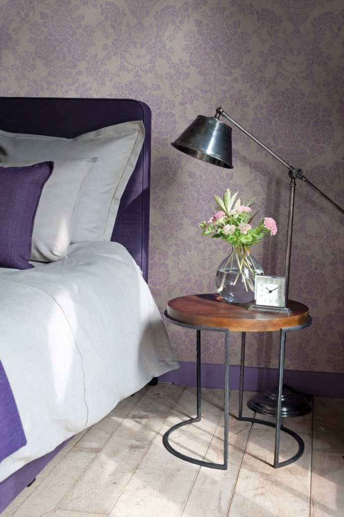 the latest wallpaper from Arte featuring a purple and beige floral print next to a purple double bed