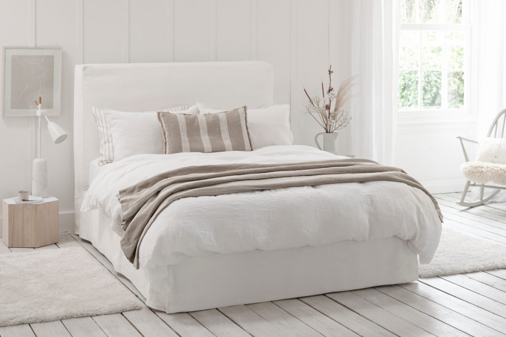 oversized cushions on a white double bed in a room full of neutral decor
