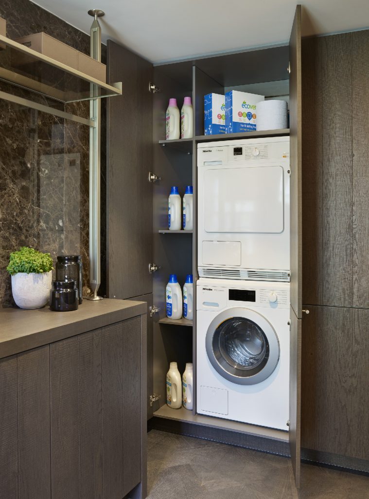 a laundry room with a washing machine, a tumble dryer, dark wood cabinetry and brass profiles