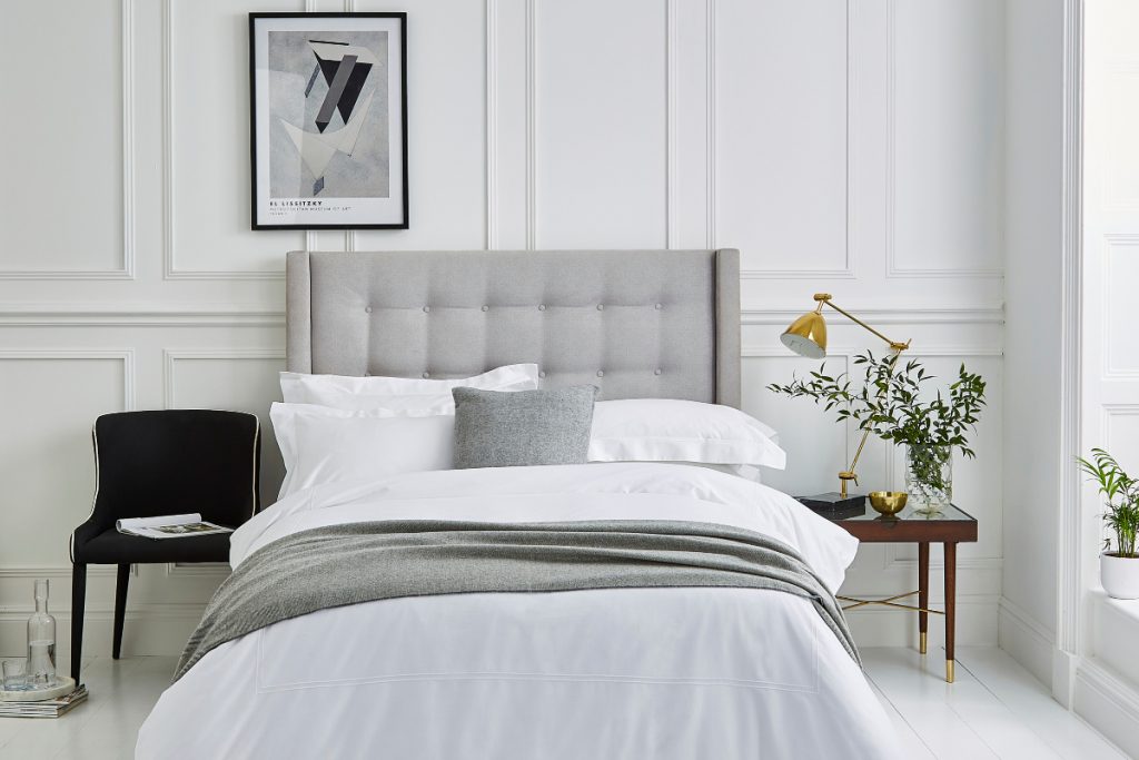 a guest bedroom featuring a grey double bed with grey and white bedding