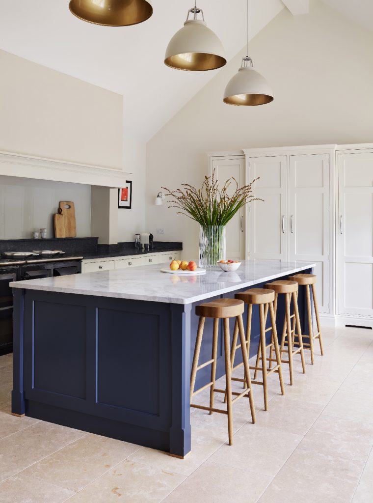 a Martin Moore design with wooden stools under a marble island with navy cabinetry