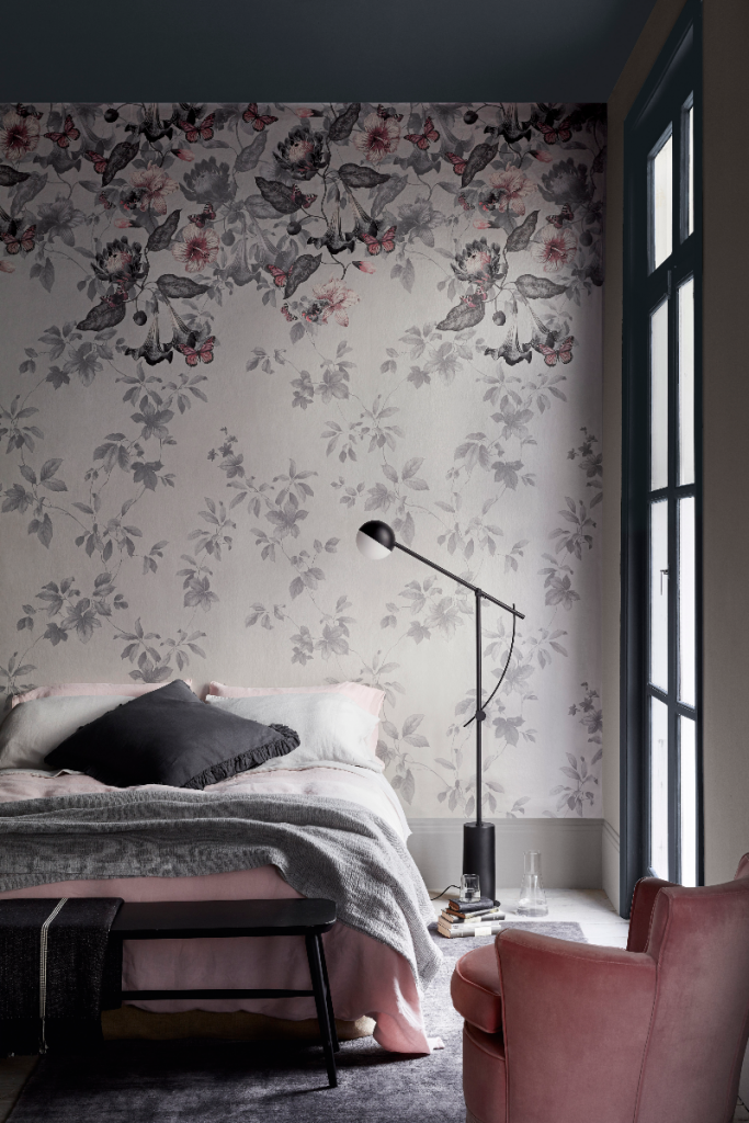 the latest wallpaper from Little Greene in a muted grey floral pattern, next to a black anglepoise floor lamp and small double bed