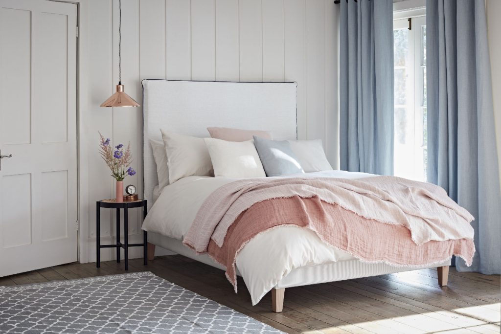 a guest bedroom featuring a large bed with lots of cushions in neutral colours