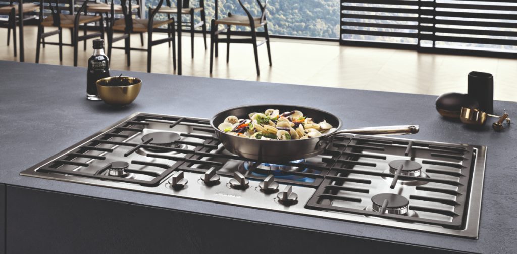 a stainless steel gas hob with a pan full of vegetables on it