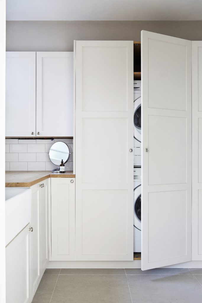 white Shaker panelled doors hiding a washer and dryer in a laundry room