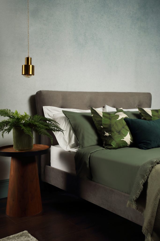 a guest bedroom with a grey double bed with green cushions