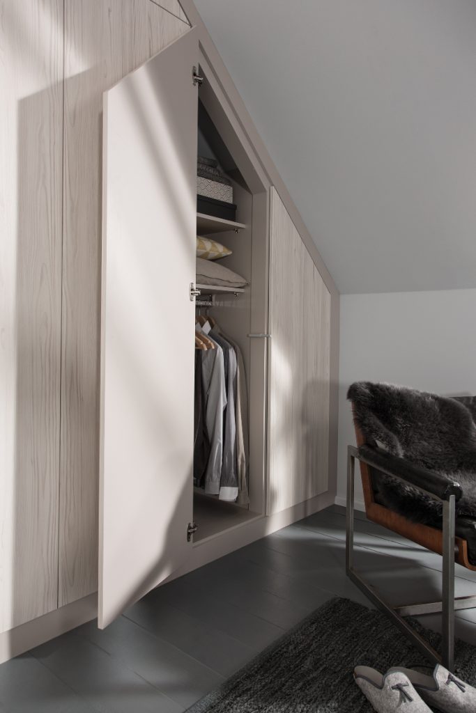 a guest bedroom with a sloping fitted wardrobe in ash wood