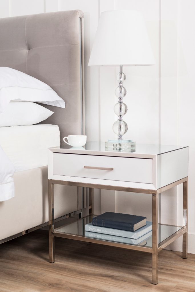 a pink double bed next to a side table with a table lamp 