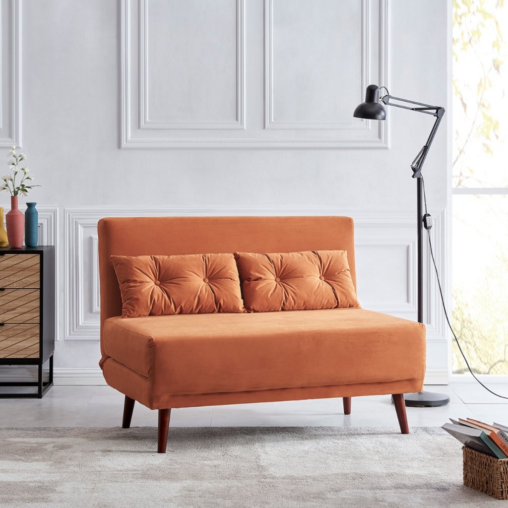 the DaAl Orange Velvet sofa with orange cushions in a large room with white wall panelling and a black angle poise lamp