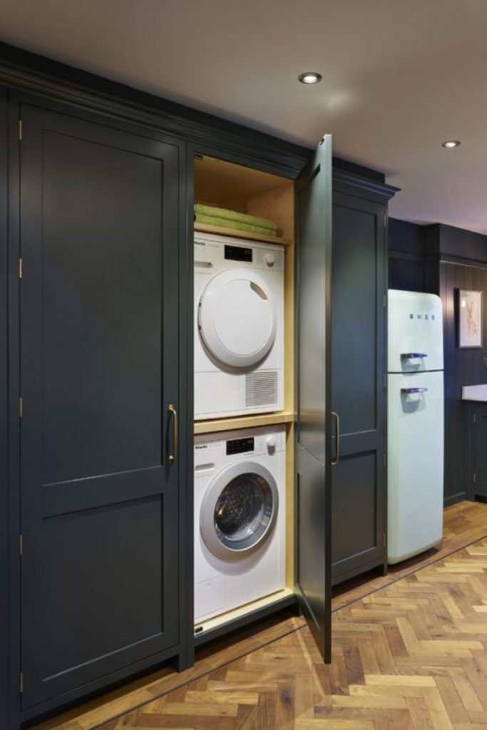 a utility room featuring anthracite cabinetry and a washing machine and tumble dryer stacked on top of each other