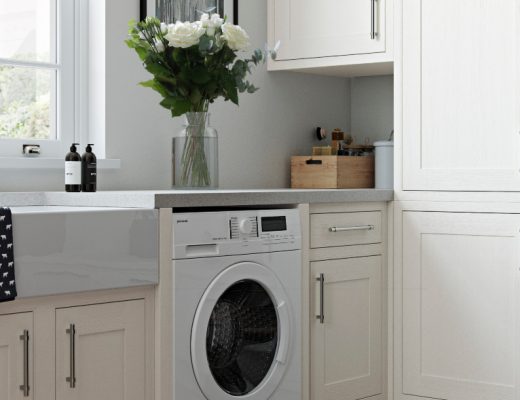 a utility room featuring pale cream shaker cabinetry with silver handles, a washing machine, and a vase of white flowers on top