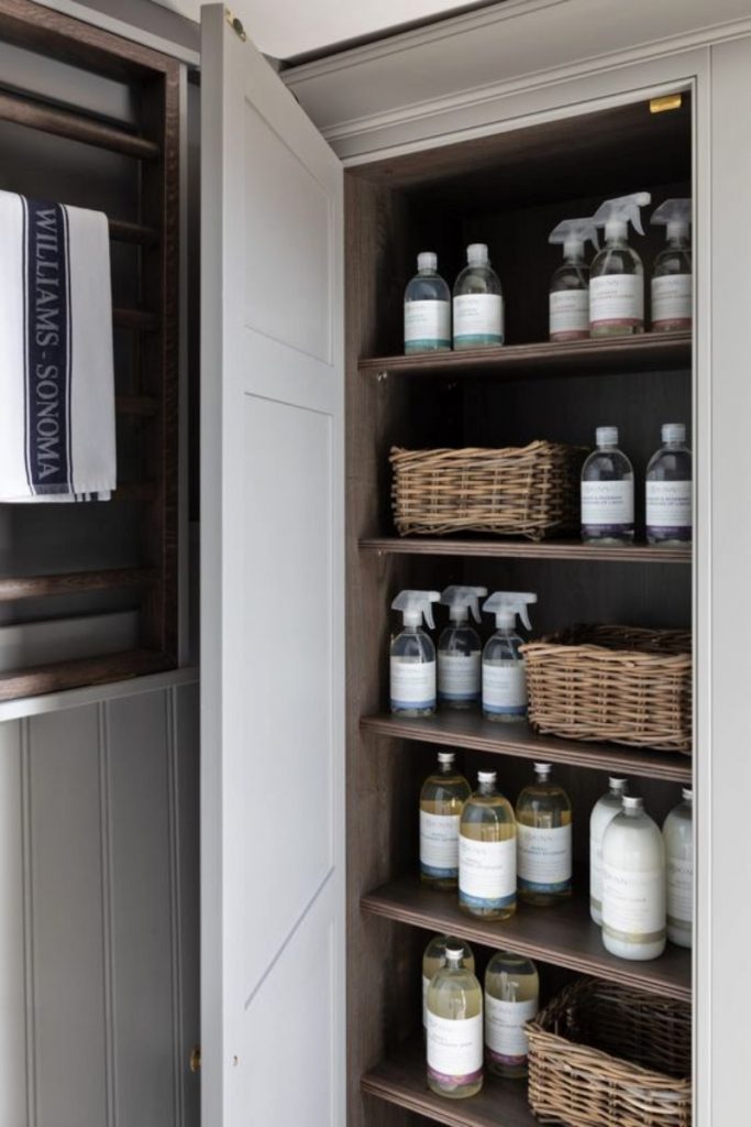 a utility room cupboard featuring lots of bottles and wicker baskets