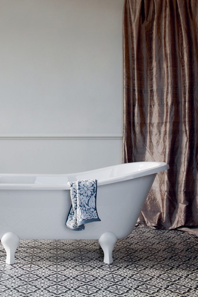 the Burlington Buckingham slipper tub in front of a full-length shiny brown curtain