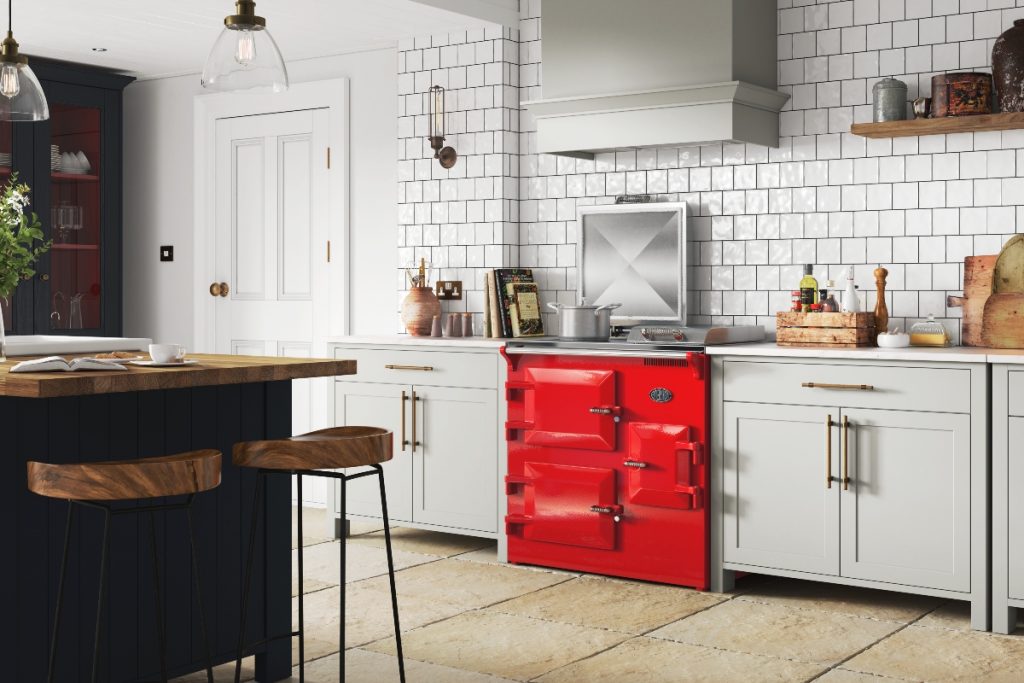 a bright red freestanding range cooker in a Shaker kitchen in light grey cabinetry with brass handles and white metro brick tiles