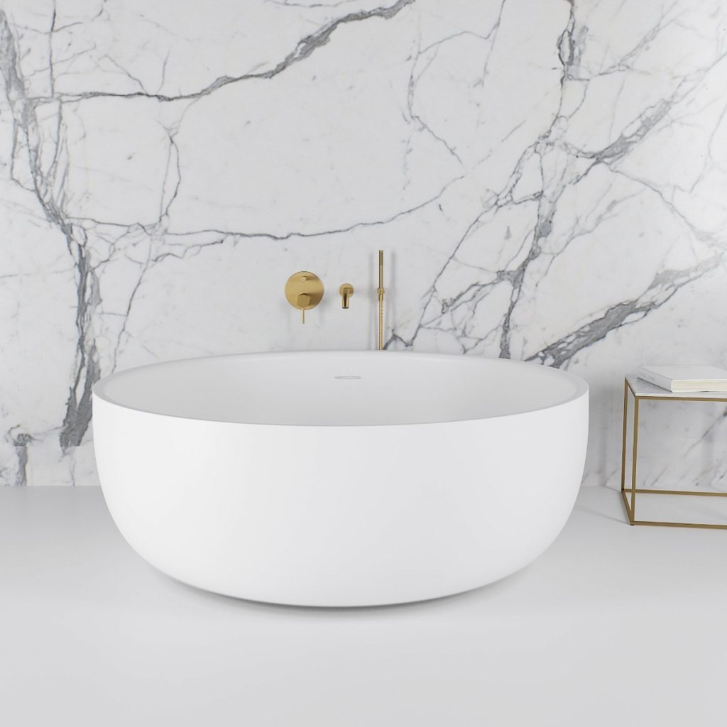 a white Lusso stone tub in a marble bathroom with brass taps