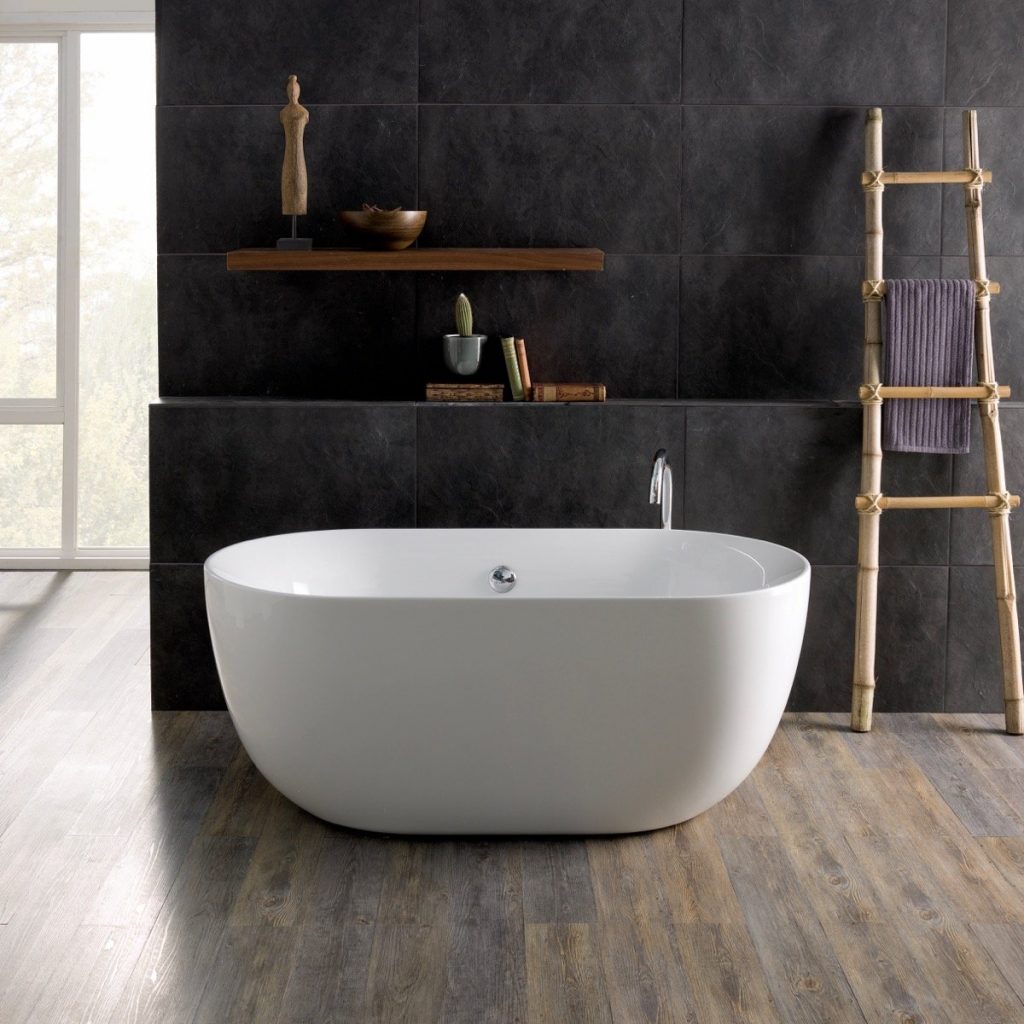 a freestanding white compact bath in a black bathroom with toiletries and accessories 