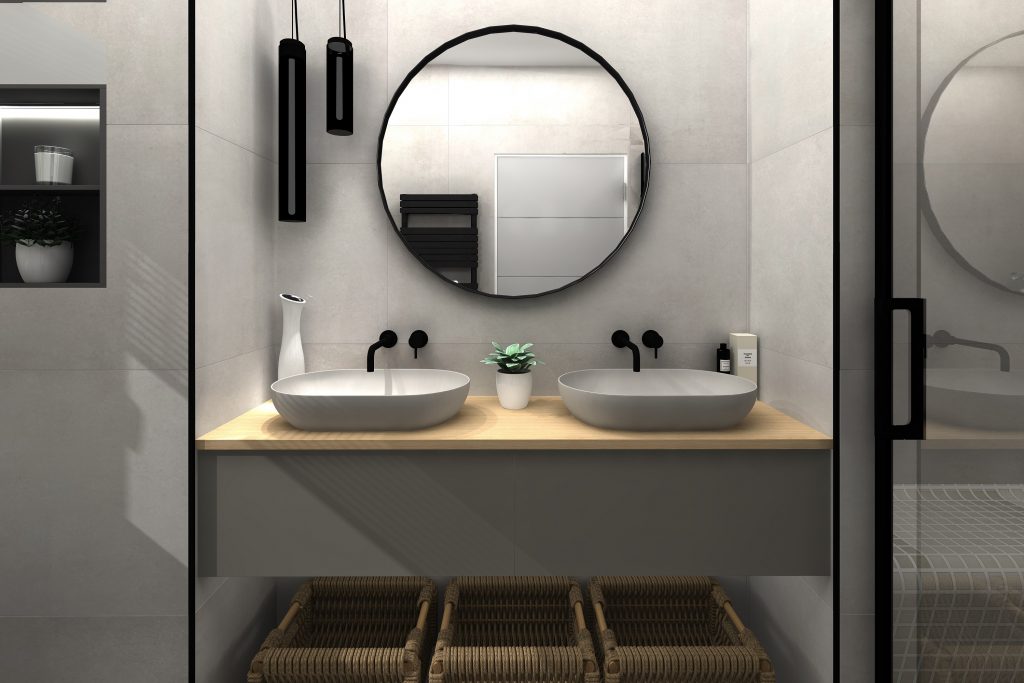 two grey basins on an oak and grey vanity unit with a round black-framed mirror with three rattan baskets underneath