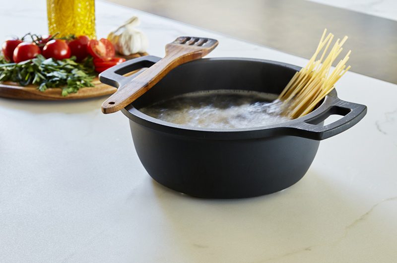 a pot of spaghetti cooking next to a platter of vegetables