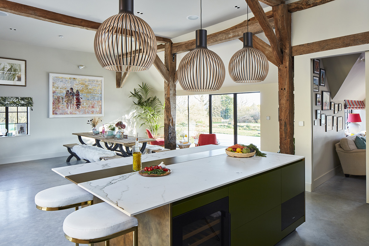 a Sola Kitchens design with a brass and white marble island and three pendant lights hanging above it