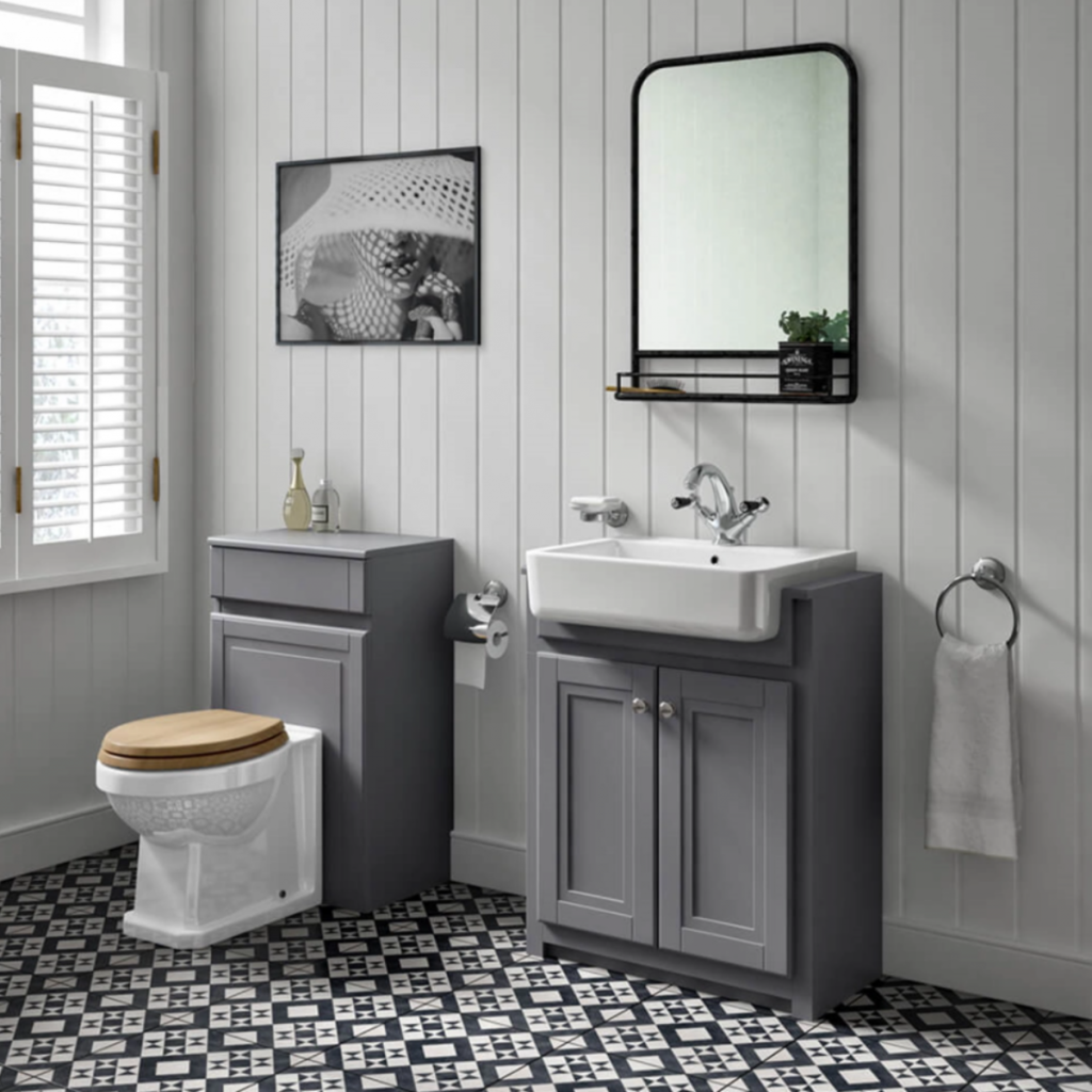a grey bathroom with light grey wall panels, monochrome floor tiles, mid grey shaker cabinetry and a toilet with a wooden seat