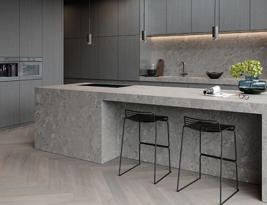 a grey kitchen with dark grey handleless cabinetry and a stone kitchen island with black bar stools