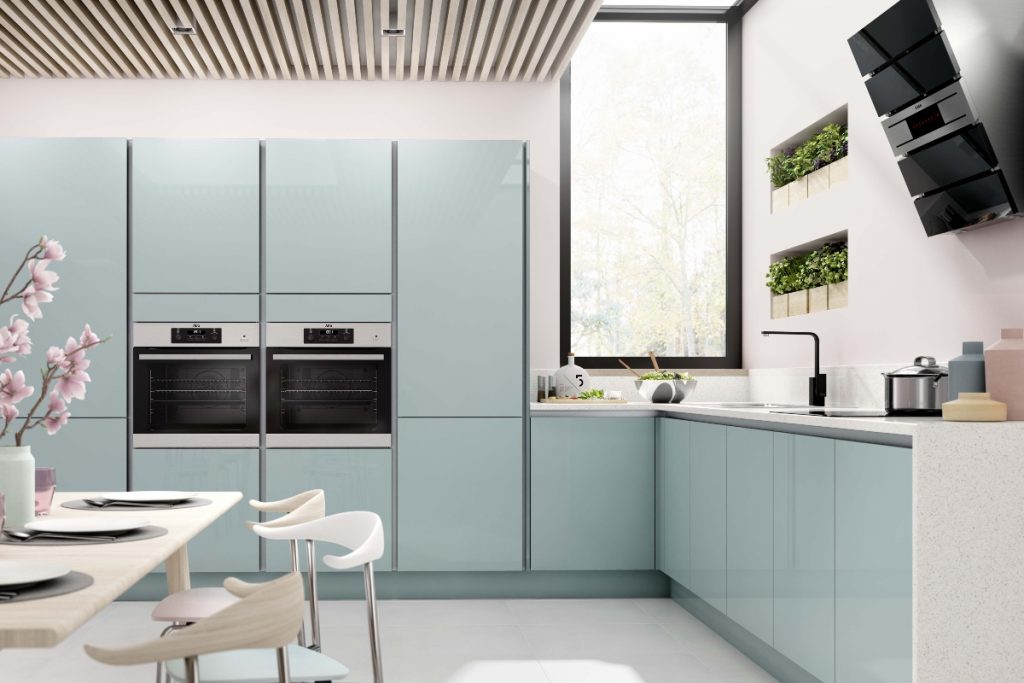 pale blue handleless kitchen units with an ash wood dining table and three dining chairs