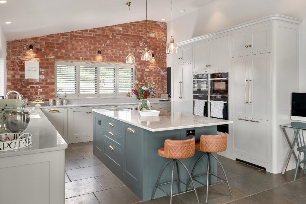 exposed brickwork and white cabinetry with two tan bar stools at an island