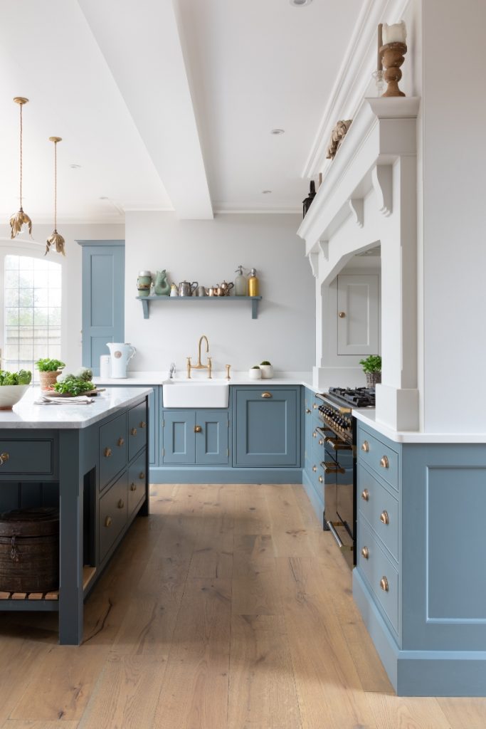 a white and blue Shaker kitchen with traditional Victorian features and a Belfast sink with brass taps