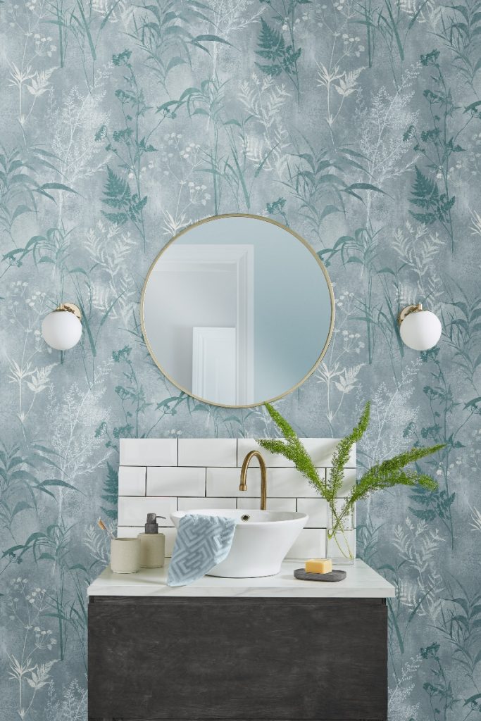 blue floral wallpaper in a small bathroom with a white metro brick splashback behind a round sink on a countertop