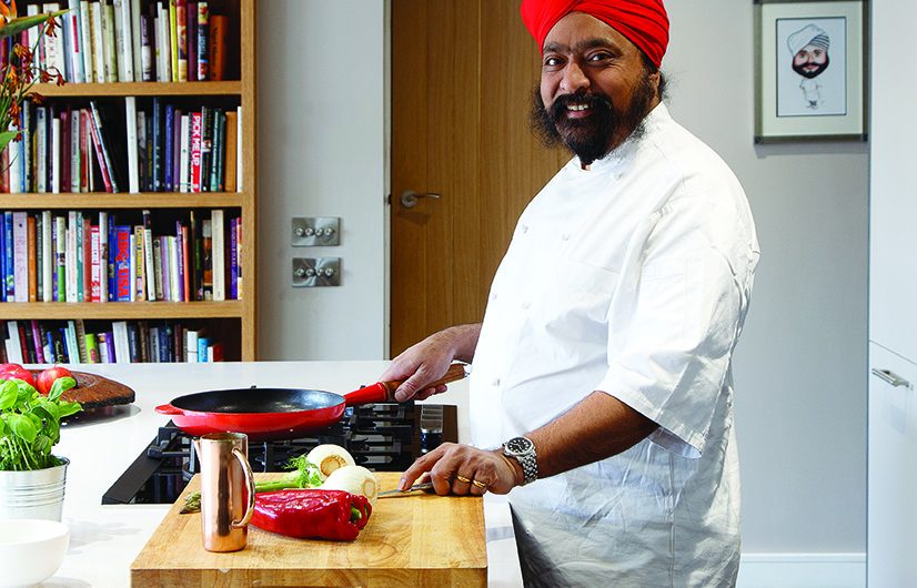an Asian man in a red turban preparing food at a hob