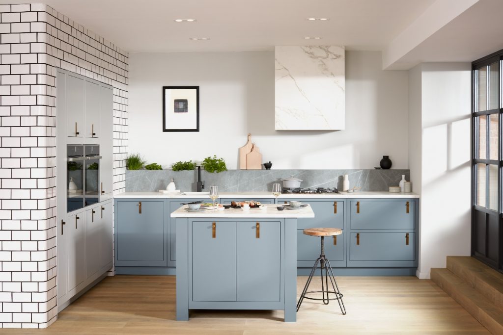 pale blue kitchen units with brass handles and a White Island in the middle of a large kitchen
