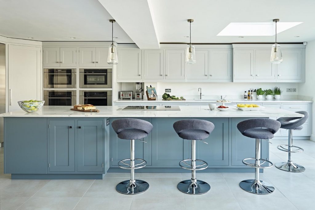 pale blue kitchen Shaker units with three blue bar stools at a long white kitchen island