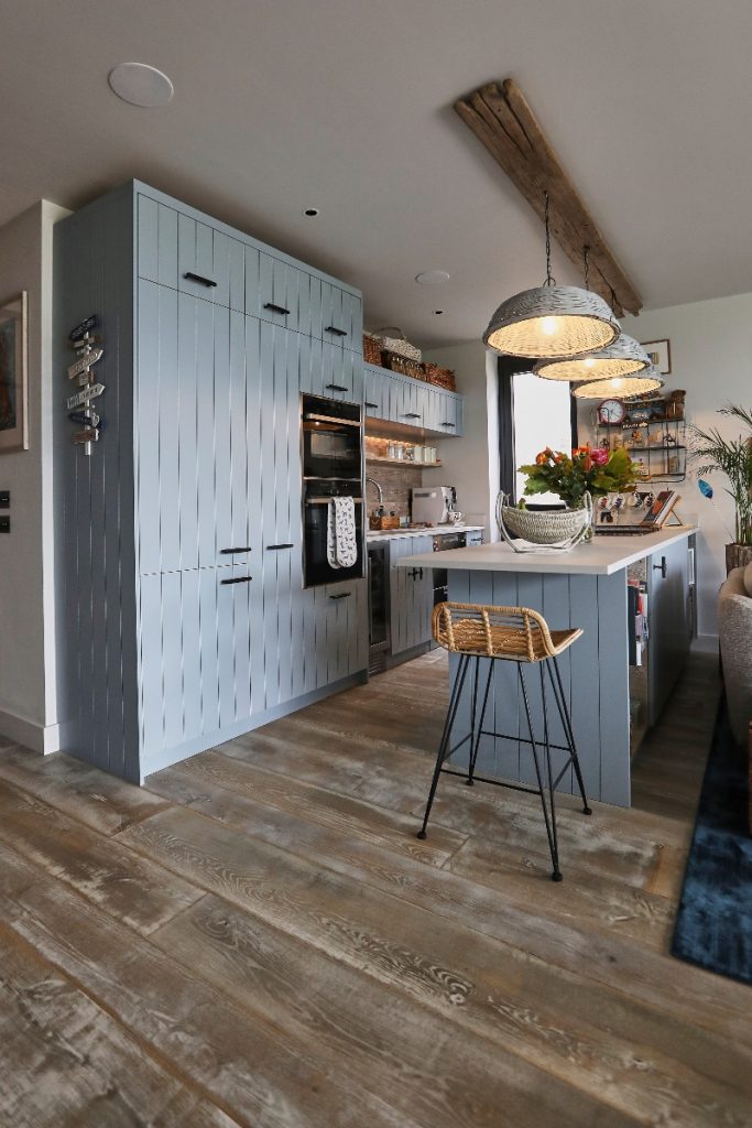 panelled cabinetry and an island with three rustic pendant lights above it