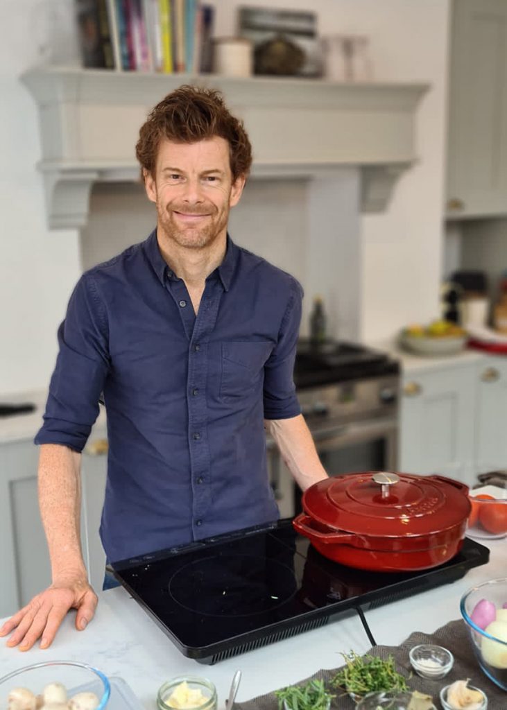 a man standing in front of a red pan on an induction hob