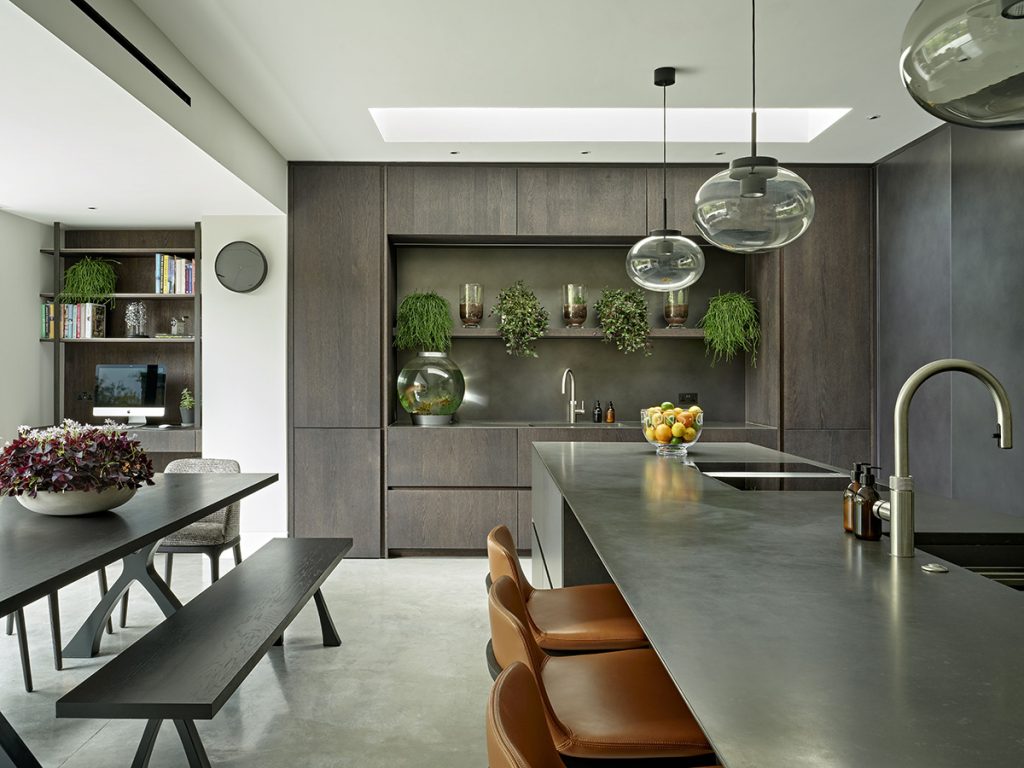 a stylish kitchen designed by an interior designer featuring a large dark kitchen island and three tan leather bar stools