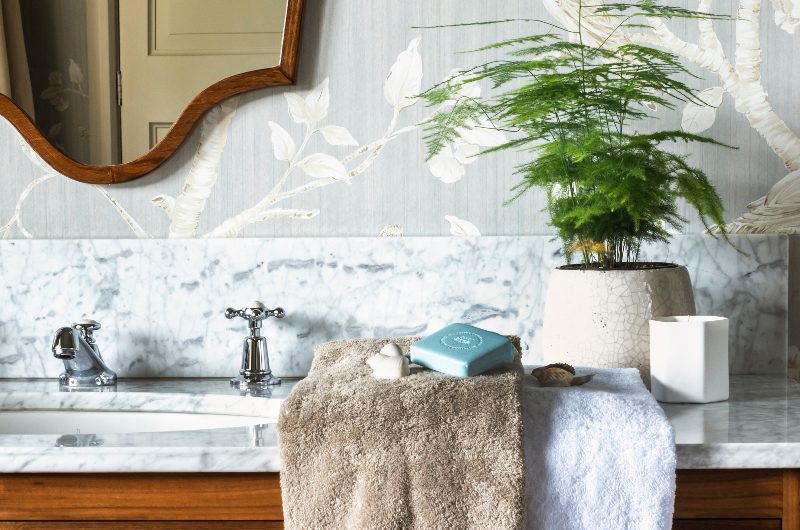 a guest bathroom featuring two brown and white towels on a marble vanity unit, traditional chrome taps and walnut cabinetry