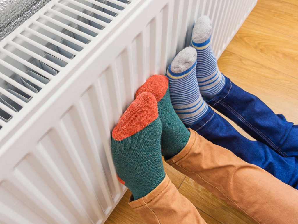 people warming their feet on a radiator