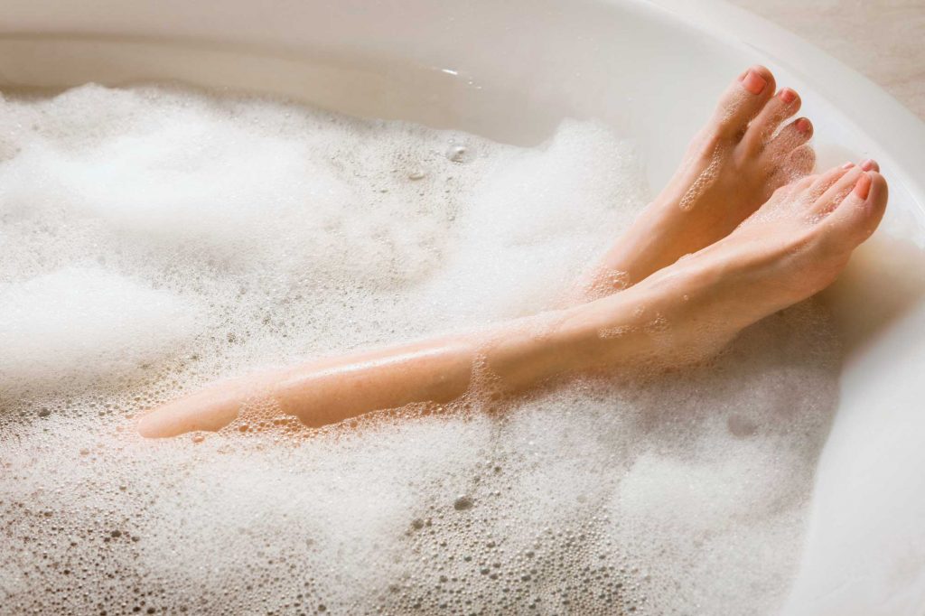 woman having half-filled bath to keep down energy costs
