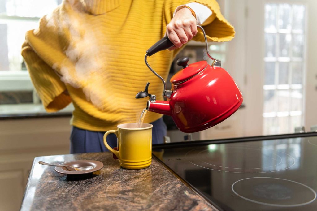 woman pouring boiling kettle to keep energy costs down